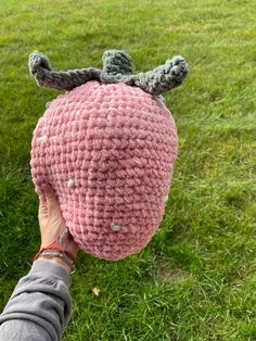 a person is holding up a crocheted pink apple with antlers on it