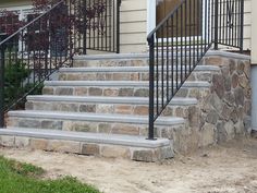 a set of stone steps leading up to a house with wrought iron railing and handrails