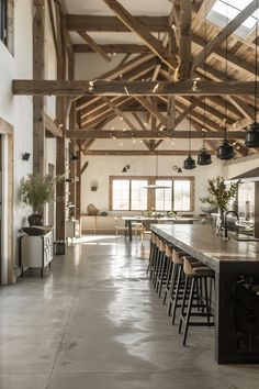 a large open kitchen and dining area with wooden beams on the ceiling, along with bar stools