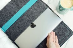 a person is holding an apple laptop in their hand and using the cover to open it