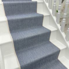 blue carpeted stairs with white railings and handrails