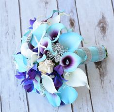 a bridal bouquet with blue and white flowers on a wooden surface, ready to be used as a brides bouquet