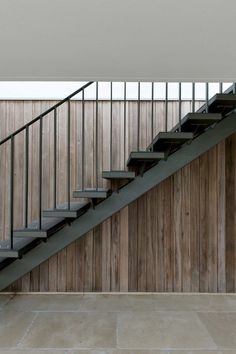 a man riding a skateboard down the side of a metal hand rail next to a wooden wall