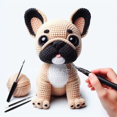 a small crocheted dog sitting on top of a table next to knitting needles