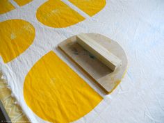 a piece of wood sitting on top of a yellow and white table cloth with circles