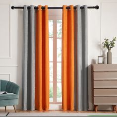 an orange and grey curtain hangs in front of a window with a chair next to it