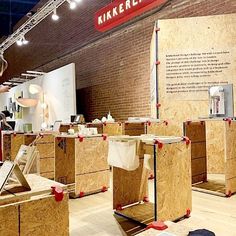 the interior of a store with wooden boxes on display in front of brick wall and ceiling