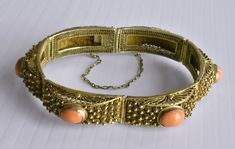 This is a very fine vintage Chinese gold gilt silver filigree hinged bracelet with 6 high quality and high density genuine and natural bezel-set oval salmon red coral cabs. Marked "SILVER". In great vintage condition. It measures 7-1/4" long by 1/2" wide and weighs 29.8 grams. Each of the 6 coral cabs measures 10 mm x 8 mm each.  From the 1940's. Antique Oval Bangle For Formal Occasions, Formal Coral Jewelry With Cabochon Details, Formal Coral Jewelry With Cabochon, Vintage Oval Coral Jewelry, Vintage Coral Oval Jewelry, Coral Oval Jewelry For Weddings, Oval Hinged Jewelry For Formal Occasions, Formal Oval Hinged Jewelry, Handmade Oval Bangle For Formal Events