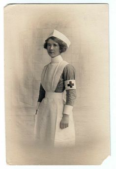 an old black and white photo of a woman wearing a nurse's outfit with a cross on it