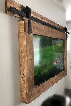 a painting hanging on the wall next to a wooden frame with black metal straps and a barn in the background