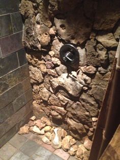 a bathroom with a stone wall and toilet in the corner, next to a tiled floor