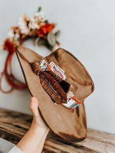 This burnt, distressed, felt fedora hat is a size 22 1/2 inches around.The hat band is an aztec and genuine leather band with a leather feather accent as well as a real feather and playing cards. This hat is burnt so it might have a slight smell for a few weeks.All feathers are glued to hold on the hat.FREE SHIPPING ON ALL OUR HAT ORDERS!All hats are branded by ©The Kiersten Zile CollectionNeed a Custom order? Message the Shop and we can start on that for you! Leather Flat Brim Fedora For Festivals, Distressed Adjustable Country Hat Band, Distressed Brown Hat For Rodeo, Western Distressed Brown Hat, Distressed Adjustable Fedora For Rodeo, Rustic Leather Hats For Festival, Distressed Brown Western Hat, Distressed Bohemian Hat For Festivals, Rustic Adjustable Distressed Hat Bands