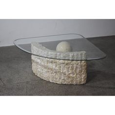 a table with a glass top and two balls sitting on the base, in front of a white wall