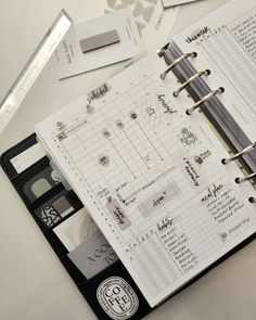 an open planner book sitting on top of a table next to a pen and ruler