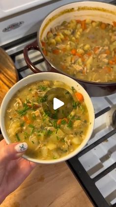 a person holding a bowl of soup in front of an oven