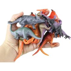 a hand is holding several toy dinosaurs in different colors and sizes, including orange, green, purple, and blue