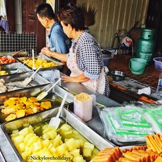 two people preparing food at an outdoor market