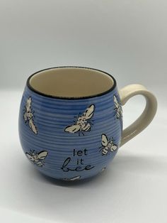 a blue and white coffee cup with bees on the side, says let it bee