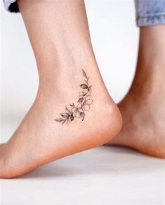 a woman's foot with a flower tattoo on the side of her leg,