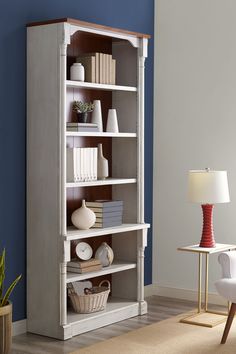 a white bookcase in a living room with blue walls