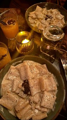 a table topped with plates and bowls filled with food next to glasses of orange juice