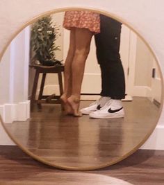 two people standing in front of a mirror with their feet on each other's legs