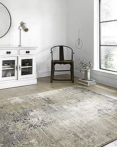 a living room with white furniture and a large rug on the floor in front of a window