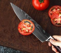 a person holding a knife over a cutting board with tomatoes and carrots