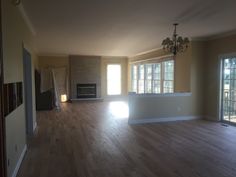 an empty living room with hard wood floors and large windows in the wall to the right