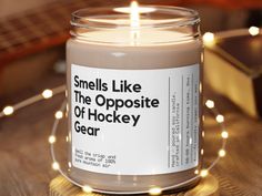 a candle is sitting on a table with some lights around it that says smells like the opposite of hockey gear