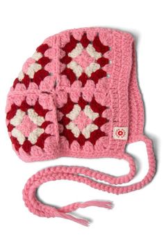 a crocheted pink hat with white and red squares on it's side