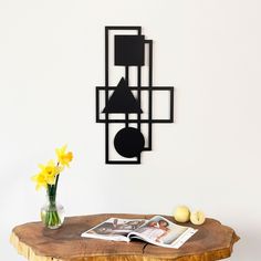 a wooden table topped with a vase filled with yellow flowers next to a wall mounted clock