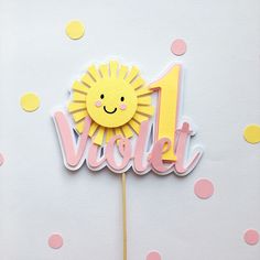 a pink and yellow cake topper with the number one on it's stick