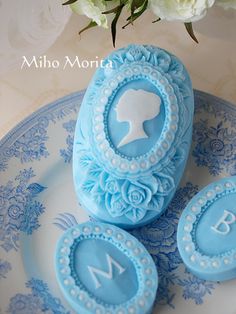 blue decorated cookies sitting on top of a plate next to white flowers and a vase