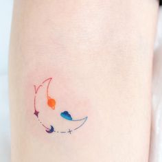 a woman's leg with a small tattoo on the side of her thigh that has an orange, blue and red cat sleeping on it