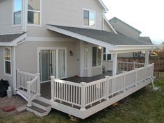 a white house with stairs leading up to the front door and back porch area on grass