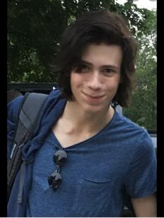 a young man wearing a blue shirt and backpack