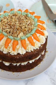 a carrot cake with white frosting and sprinkles on top sits on a plate