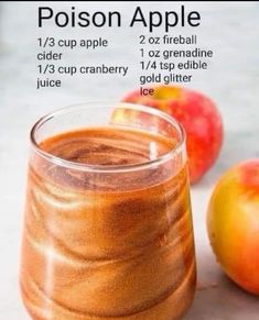 a glass filled with liquid next to some apples