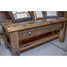 a wooden table with two framed pictures on top and one empty shelf below the coffee table