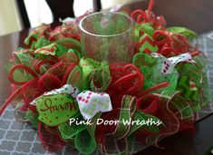 a christmas wreath sitting on top of a table next to a glass vase with a candle in it