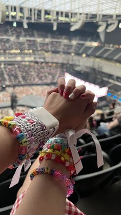 a person with bracelets on their arm at a baseball game in a stadium filled with people