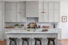 a large kitchen with white cabinets and marble counter tops, along with bar stools