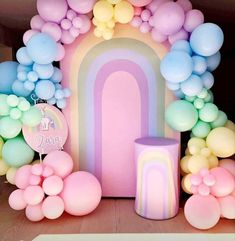 there are balloons and other decorations on the floor in front of a rainbow - themed backdrop