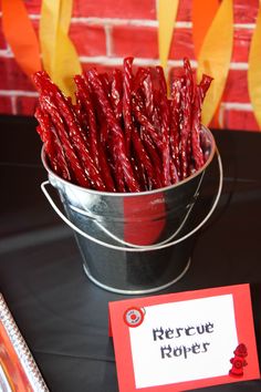 a bucket full of red peppers sitting on top of a table next to a sign