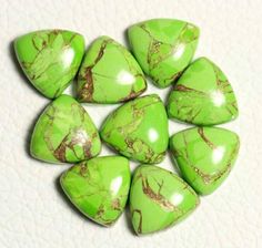 green and gold colored stones sitting on top of a white surface