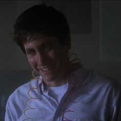 a young man smiles at the camera while wearing ear rings