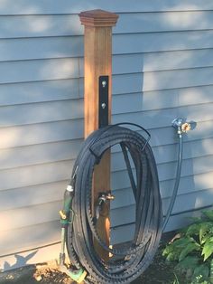 a hose is attached to the side of a house with a wooden pole in the background