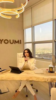 a woman sitting at a table with a laptop in front of her and the words youmi above her