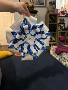 a person is holding up a blue and white hair bow on a table in a living room